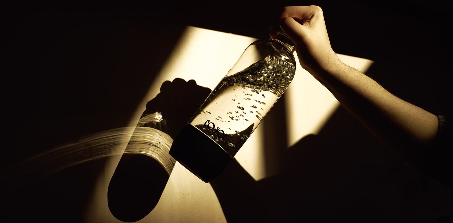A CO2 YOU bottle of sparkling water held in a shaft of light