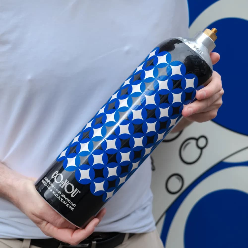 A CO2 YOU 1.65kg cylinder held beside a sparkling water tap
